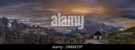 Nächtlicher Blick auf die Bergkapelle in der Nähe von Tre Cime di Lavaredo in den Dolomiten, mit den Lichtern des Auronzo Rifugio im Hintergrund. Italien Stockfoto