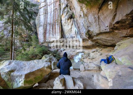 Wanderer macht Pause, gefrorener Wasserfall mit Eiszapfen in der Gautschgrotte, Hohnstein, Sachsen, Deutschland *** Wanderer macht Pause, gefrorenes Wasser Stockfoto