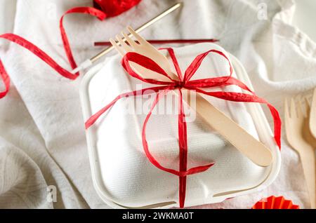 Weiße bento-Kuchenbox mit roter Schleife. Geschenkbox mit leckerem bento. Kuchenverpackung. Lieferung. Stockfoto