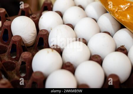 In einem recycelten Karton liegen ein Dutzend frischer Eier an einem lebhaften Marktstand Stockfoto