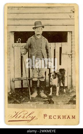 Original viktorianische Carte de Visite (Visitenkarte oder CDV) eines Arbeiters - ein Schäfer mit hohem gekröntem Bowler Hut, mit einem Gauner, mit Lederstiefeln mit geknöpften Gamaschen, mit seinem treuen Collie Schäferhund. Der Mann könnte seine Schafe auf dem Weg zu den Fleischmärkten Londons wie Smithfields von so weit wie Wales getrieben haben. Vielleicht ein Waliser. Viele Schäfer weideten ihre Tiere auf dem Common in Peckham Village, bevor sie nach London gingen. Fotograf: Theophilus Claudius Kirby, Peckham, SE. London, Borough of Southwark, UK Circa 1880's Stockfoto