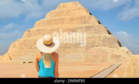 Sakkara, Ägypten; 11. November 2023 - Eine blonde Frau steht vor der ältesten stehenden Stufenpyramide Ägyptens. Es befindet sich in Sakkara Stockfoto