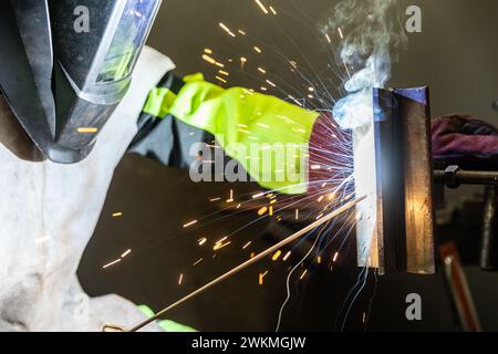 Detail zum Schweißprozess von Metallteilen, mit einer Schweißmaschine, helle Funken und Blitze, Industriekonzept Stockfoto