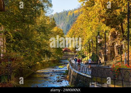 Polanica-Zdroj, Polen - 21. Oktober 2023: Schöne Aussicht mit Bystrzyca Dusznicka Fluss zwischen hohen Bäumen und Büschen und langer Promenade mit Spaziergang Stockfoto