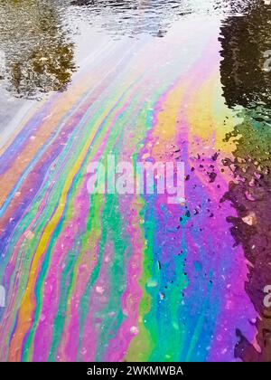 Farbige Textur von Ölprodukten auf Asphalt im Regen. Stockfoto
