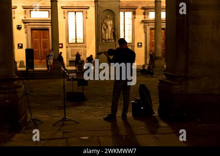 Busking in Italien ist eine altehrwürdige Tradition, bei der Musiker auf den Straßen spielen, um Trinkgeld zu erhalten. Ein Mann spielt nachts in der Nähe der Uffizien Geige. Stockfoto