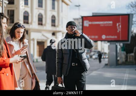 Eine Gruppe junger Unternehmer im Freien, mit einem stilvollen Mann, der telefoniert und einer konzentrierten Frau, die ein Smartphone benutzt. Stockfoto