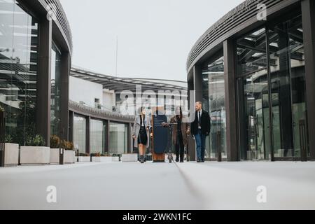 Drei junge, multirassische Geschäftspartner gehen in einem modernen urbanen Umfeld zusammen und führen ein Gespräch. Stockfoto