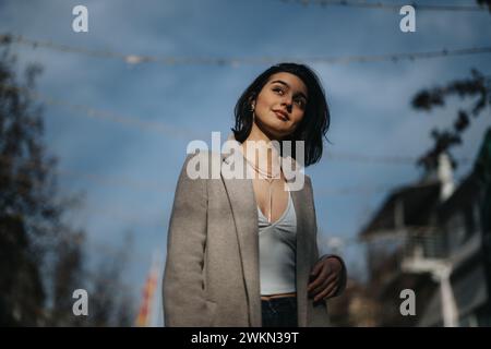 Ein stilvolles Mädchen schlendert an einem Herbsttag durch die Straßen der Stadt und strahlt Selbstvertrauen und lässige Eleganz aus, die typisch für Teenager-Mode sind. Stockfoto