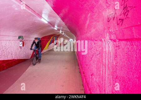 Ein Radfahrer fährt durch einen hellrosa Tunnel am Ostbahnhof in München Stockfoto