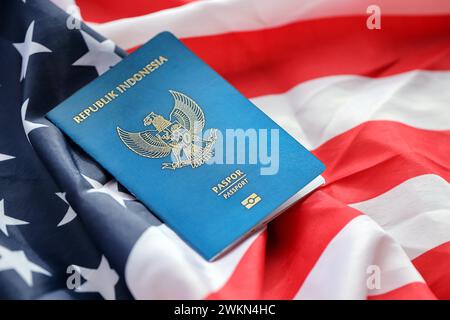 Pass der blauen Republik Indonesien auf dem Hintergrund der Nationalflagge der Vereinigten Staaten aus nächster Nähe. Tourismus und Diplomatie Stockfoto