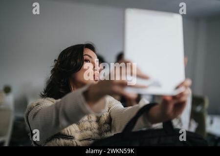 Brünette Frau, die ein Selfie mit Tablet in der Pause von der Arbeit in einem modernen Büro macht. Stockfoto