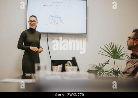 Geschäftsfrau hält Präsentation auf dem fernsehbildschirm in einem modernen Tagungsbüro. Stockfoto