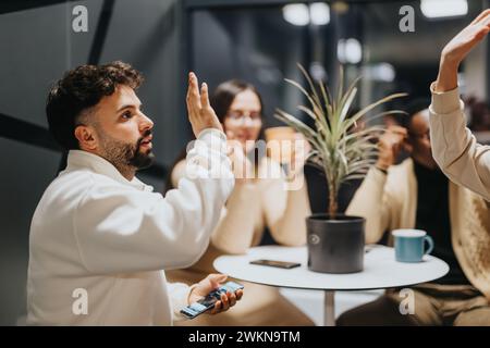 Geschäftsmitarbeiter, die gemeinsam eine Pause einlegen. Sie genießen die gemeinsame Nachtarbeit in positiver Atmosphäre. Die Leute geben einander High-Five. Stockfoto