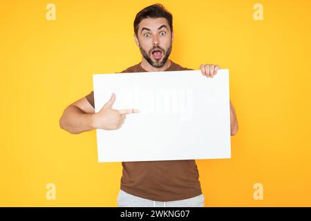Mann mittleren Alters mit leerem Plakat. Darstellung des Kopierbereichs für Ihren Text oder Ihr Design. Ein Mann, der eine leere Werbetafel im Studiohintergrund zeigt Stockfoto