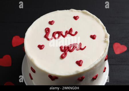 Bento Kuchen mit Text Love You und Papierherzen auf schwarzem Tisch, Nahaufnahme. St. Valentinstag-Überraschung Stockfoto