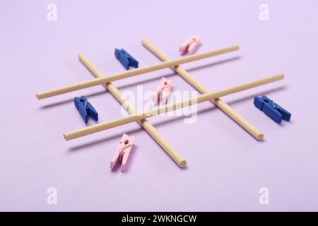 TIC Tac Toe Spiel mit Klamotten auf Fliederhintergrund Stockfoto