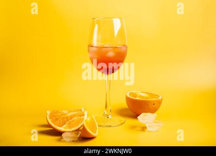 Cocktail Aperol Spritz mit Orangen und Eis auf hellgelbem Hintergrund Stockfoto