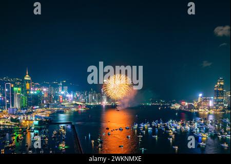 Das Feuerwerk brach hell über der Skyline der Stadt über dem Nachthimmel und spiegelte sich im ruhigen Wasser darunter Stockfoto