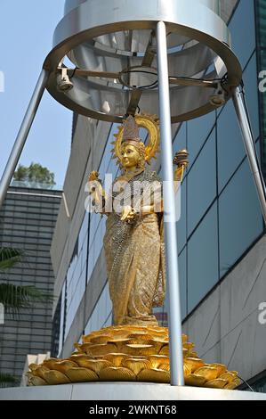 Lakshmi ist eine der wichtigsten Göttinnen im Hinduismus, die hier als elegante, goldfarbene Frau dargestellt wird, die auf einem Lotus in einem Bangkok-Schrein steht Stockfoto