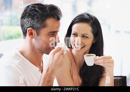 Fröhlich, Gespräch und Paare mit Kaffee zum Date für Romantik oder Jubiläum in der Cafeteria. Liebe, Bindungen und junge Männer und Frauen reden und trinken Stockfoto