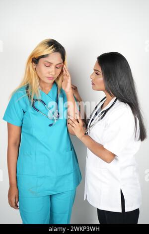 Eine junge Frau, die sich mit ihrem Arzt unterhält, in medizinischen Schutten gekleidet und mit einem Stethoskop ausgestattet ist Stockfoto
