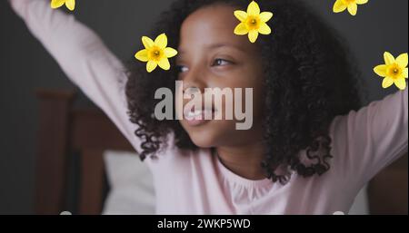 Bild von Blumen über dem afroamerikanischen Mädchen, das aufwacht Stockfoto