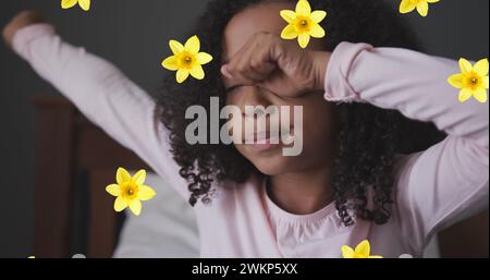 Bild von Blumen über dem afroamerikanischen Mädchen, das aufwacht Stockfoto