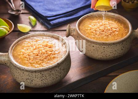 Arabische Küche; Zitrone auf traditioneller orientalischer Orzo-Suppe oder Vogelzungensuppe. Es ist köstliche Hühnerbrühe mit Orzo-Pasta. Stockfoto