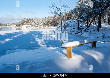 Holzbank mit Schnee in der Nähe des Sees Vattern Motala Schweden Stockfoto