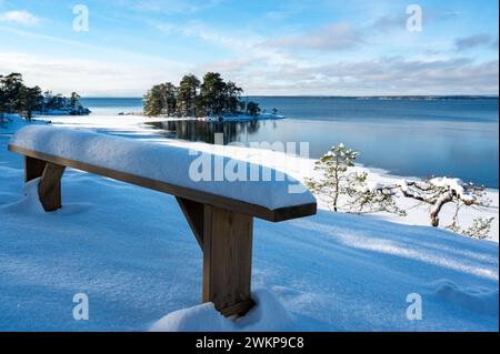 Holzbank mit Schnee in der Nähe des Sees Vattern Motala Schweden Stockfoto