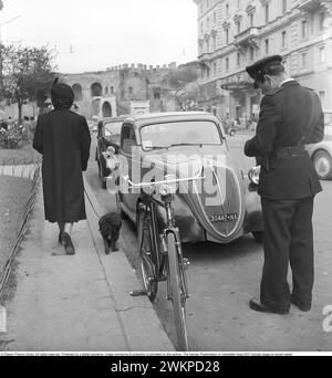 In Italien in den 1950er Jahren Ein Verkehrswächter auf der Straße, der ein Ticket für das geparkte Auto schreibt. Mailand Italien 1950. Foto Kristoffersson Ref. DV19 *** Lokale Bildunterschrift *** © Classic Picture Library. Alle Rechte vorbehalten. Geschützt durch eine digitale Signatur. Bildüberwachung und -Schutz ist auf diesem Bild aktiviert. Die Lizenz, Präsentation oder Newsletter beinhaltet KEINE Nutzung in sozialen Medien. Stockfoto