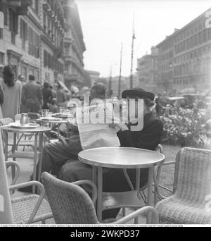 Urlaub in Italien in den 1950er Jahren Eine Frau sitzt und liest die Zeitung Rome Daily American. Laut Watergate-Journalist Carl Bernstein war der Daily American bis Anfang der 1970er Jahre zu 40 % im Besitz der Central Intelligence Agency Die Absicht dieses Besitzes war, die CIA-Agenten zu schützen und die italienischen Wähler zu beeinflussen, die zu dieser Zeit drohten, kommunistisch zu wählen. Während dieser Zeit wurde das Zeitungsbüro bombardiert und beschädigt. Mailand Italien 1950. Foto Kristoffersson Ref. AY28-11 *** Lokale Bildunterschrift *** © Classic Picture Library. Alle Rechte vorbehalten. Durch eine Ziffer geschützt Stockfoto