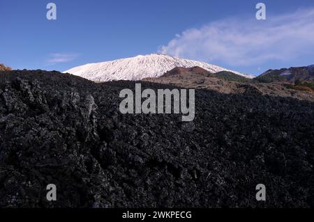 Im Schatten des alten Lavafeldes und des hellen Ätna im schneebedeckten Hintergrund, Ätna Park in Sizilien, Italien Stockfoto