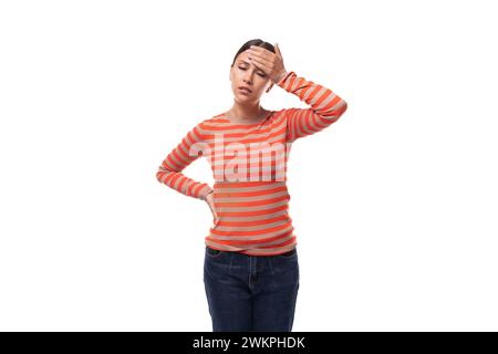 Eine 30-jährige schlanke Europäerin, die einen lässigen orangefarbenen Pullover trägt, fühlt sich müde und hat Kopfschmerzen Stockfoto