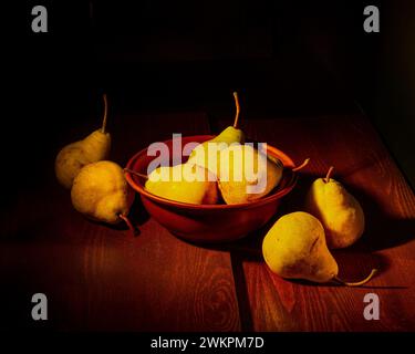 Reife gelbe Birnen auf einem Holztisch und schwarzem Hintergrund. Stillleben. Stockfoto