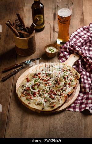 Ein Stück Peperoni-Pizza auf einem hölzernen Schneidebrett mit einem Glas Bier Stockfoto