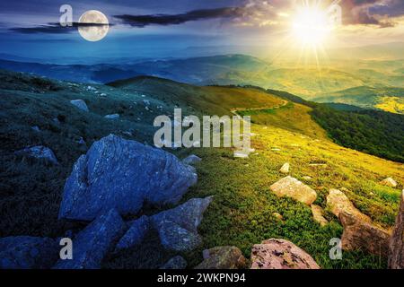Weiße Felsbrocken auf dem Hügel mit Sonne und Mond zur Sommersonnenwende. Tag- und Nachtzeitwechsel. Geheimnisvolle Landschaft im Morgenlicht Stockfoto
