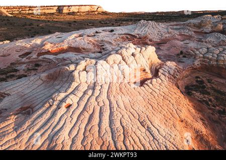 USA, ARIZONA, WHITE POCKET: Die White Pocket ist ein abgelegenes, bekanntermaßen schwer zugängliches Sandsteinstück, das sich in der Wüste des Vermillion Cliffs National Monument nahe der Grenze zu Arizona/Utah versteckt. Das gesamte Gebiet ist mit einer grauen Felsschicht bedeckt, manchmal nur wenige Zentimeter dick, über dem roten Sandstein, wo die Formationen heulen und tropfen, die die gesamte Landschaft so aussehen lässt, als wäre sie mit Puderzucker bedeckt. An manchen Stellen sind die Steinschichten völlig verdreht, wie ein riesiger Marmorkuchen. Stockfoto