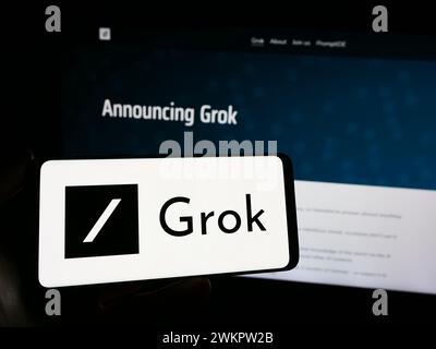Person, die ein Smartphone mit dem Logo des Chatbots Grok (X.AI) für generative künstliche Intelligenz vor der Website hält. Schwerpunkt auf dem Display des Telefons. Stockfoto