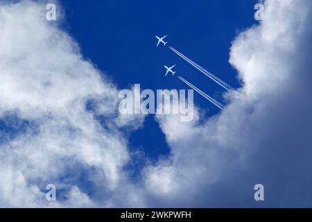 zwei weiße Passagierflugzeuge mit Vapor Trails im blauen Himmel Stockfoto