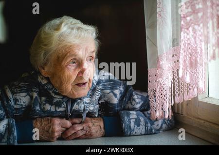 Eine ältere Frau sitzt am Fenster. Stockfoto
