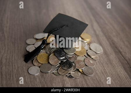 Graduierungskappe auf einem Stapel Münzen. Bildungsfinanzierung, Studentendarlehenskonzept. Stockfoto