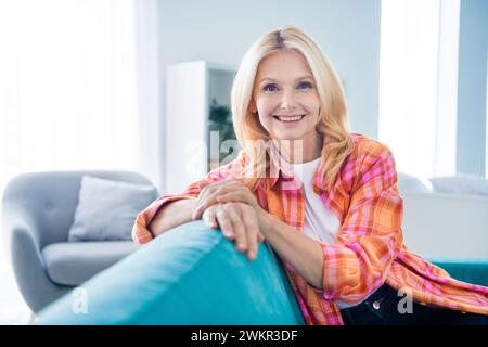 Foto einer charmanten, fröhlichen, alten Frau, die in einer neuen Wohnung sitzt Stockfoto