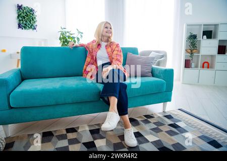 Foto einer positiven, fröhlichen, alten Frau, die auf einem großen, hellen, geräumigen Haus sitzt Stockfoto