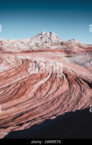 USA, ARIZONA, WHITE POCKET: Die White Pocket ist ein abgelegenes, bekanntermaßen schwer zugängliches Sandsteinstück, das sich in der Wüste des Vermillion Cliffs National Monument nahe der Grenze zu Arizona/Utah versteckt. Das gesamte Gebiet ist mit einer grauen Felsschicht bedeckt, manchmal nur wenige Zentimeter dick, über dem roten Sandstein, wo die Formationen heulen und tropfen, die die gesamte Landschaft so aussehen lässt, als wäre sie mit Puderzucker bedeckt. An manchen Stellen sind die Steinschichten völlig verdreht, wie ein riesiger Marmorkuchen. Stockfoto