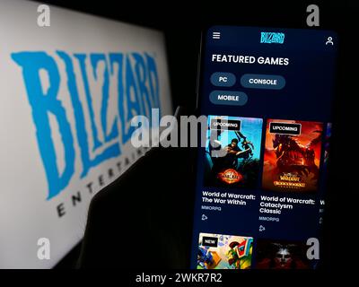 Person, die ein Mobiltelefon hält, mit der Webseite des US-amerikanischen Videospielunternehmens Blizzard Entertainment Inc. Vor dem Logo. Konzentrieren Sie sich auf die Mitte des Telefondisplays. Stockfoto