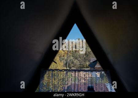 Blick auf den Herbstwald durch ein dreieckiges Fenster im Dachgeschoss Stockfoto