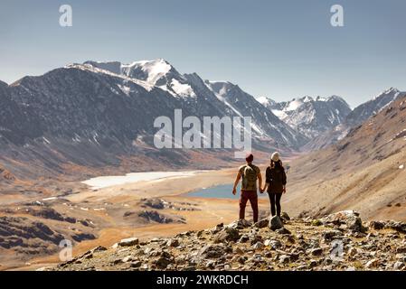 Ein paar Touristen oder Wanderer stehen auf der Bergspitze und genießen eine schöne Aussicht auf das Tal mit zwei Seen und kleinen Gletschern Stockfoto