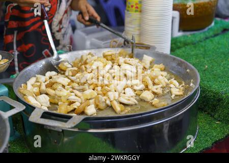 Frischer Tintenfisch, der in einer großen Pfanne auf einem geschäftigen Street Food Market perfekt gebraten wird, ein beliebter Snack bei Einheimischen und Touristen gleichermaßen Stockfoto